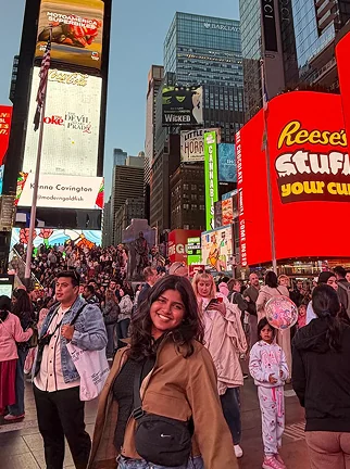 Smiling in a crowded Times Square at dusk